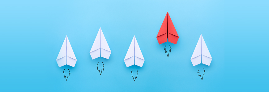 Red paper plane leading among a white planes on blue background.